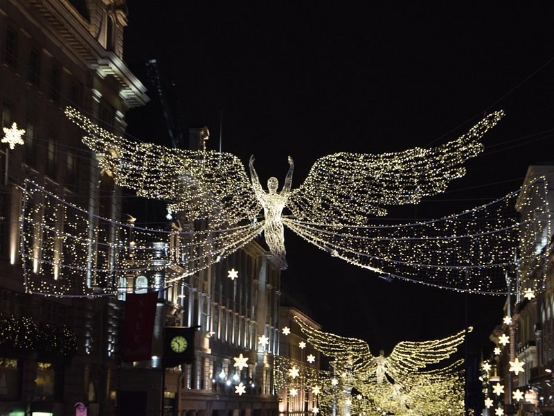 An angel of warm white lights with outspread wings against a black night sky