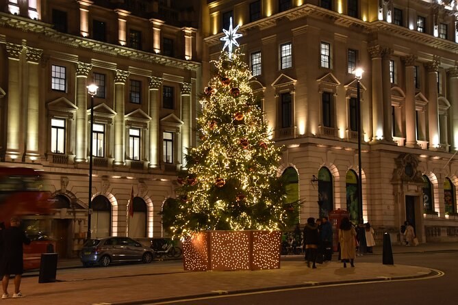 A lit Christmas tree in a stone square framed by grand lit buildings