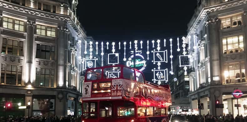 Strings of white lights hung across a wide shopping street, a double-decker below
