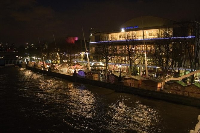 The river at night with a row of lit market huts along the far bank