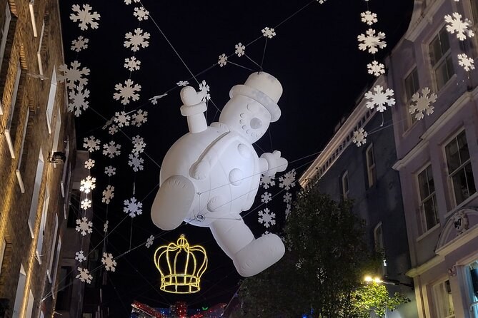 White snowflakes and a floating snowman hung high over a narrow street at night