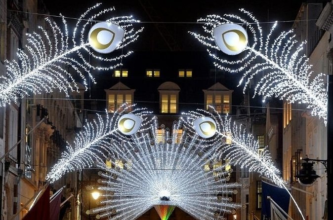 White peacock feathers made of lights fanned out above a narrow shopping street